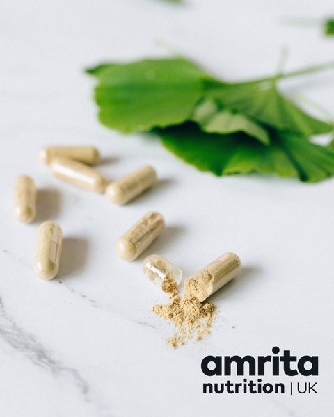 A high-key product hero shot showcasing open dietary supplement capsules and ginkgo leaves on a clean marble surface.